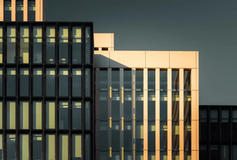 Fachada de edifício empresarial contemporâneo ao fim do dia, com janelas iluminadas