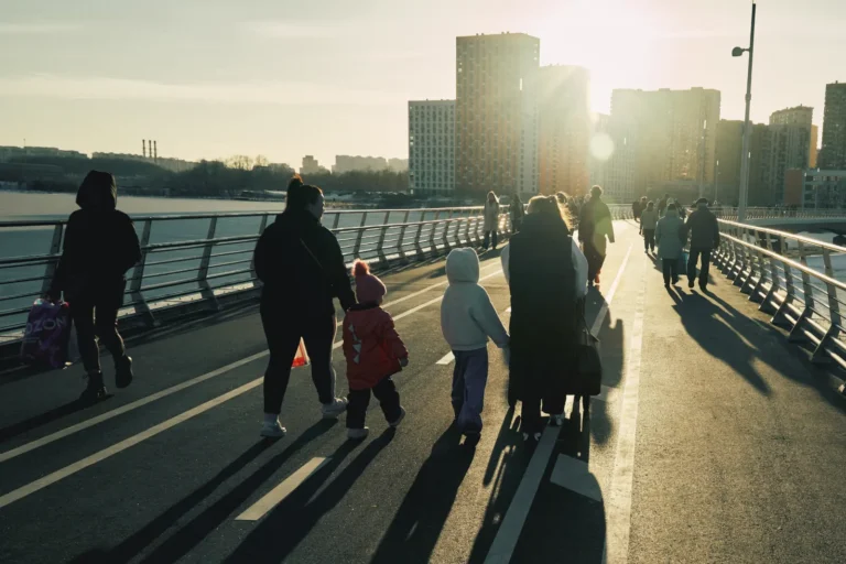 Família a caminhar junta ao pôr do sol, junto ao rio, numa cidade